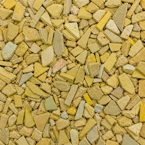 Close-up of crushed yellow and beige stone chips or gravel scattered across a surface
