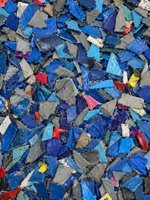 Scattered pile of colorful plastic shredded material including blue, gray, red, and yellow fragments