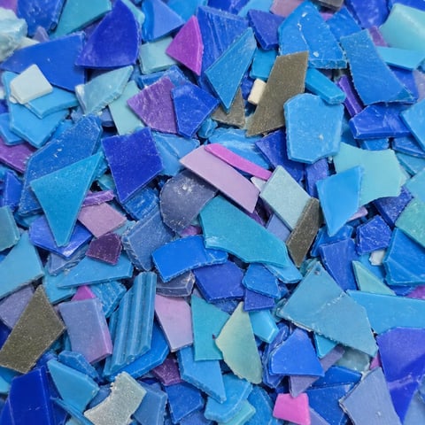 Scattered collection of blue, purple, pink, and turquoise glass or ceramic tiles and fragments