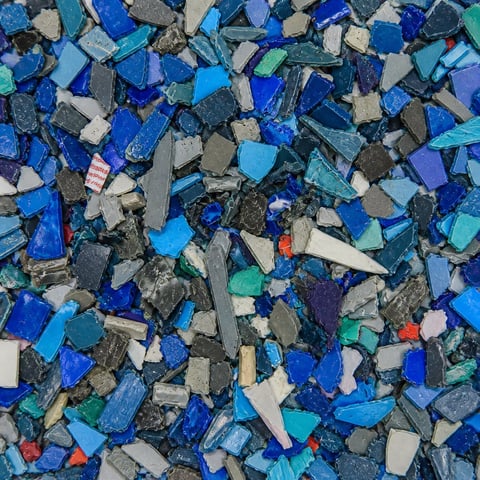 Overhead view of crushed glass and ceramic tile fragments in shades of blue, white, and gray
